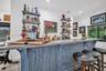 Custom built-in bar featuring a concrete countertop, plank-style wood cabinetry with cross-brace detailing, and industrial-style wall-mounted shelving