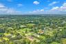 Aerial perspective of a sprawling residential landscape featuring expansive lots, mature greenery, and paved road access