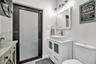 White vanity featuring a rectangular vessel sink, frosted glass cabinet inserts, and brushed nickel hardware, paired with a multi-light fixture, frame