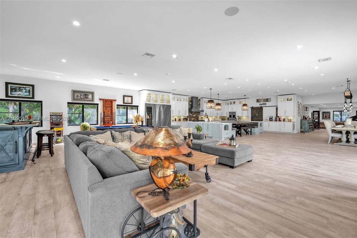 Open-concept interior featuring light wood-finish flooring, recessed lighting, and white cabinetry