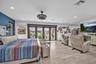 Wood-finish flooring, multi-panel sliding glass doors, recessed lighting, and a drum-style ceiling fan with an integrated light fixture
