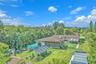 Expansive backyard featuring a sprawling lawn, mature perimeter trees, hardscaped patio, and multiple structural shade coverings