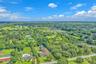 Aerial perspective of a sprawling residential property featuring a multi-gable roofline, a private in-ground swimming pool, extensive lawn space, and 