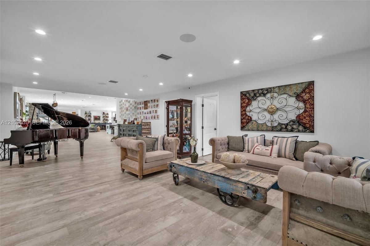 Open-concept interior featuring light-toned wood-finish flooring, recessed lighting, and integrated ceiling speakers
