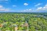 Aerial perspective of a sprawling property featuring extensive mature landscaping, a manicured lawn, and a multi-section roofline