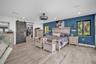 Wood-finish flooring, dark charcoal barn-style sliding door, recessed ceiling lighting, industrial-style drum ceiling fan, and blue accent wall