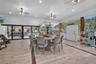 Expansive covered outdoor living area featuring wood-finish flooring, recessed lighting, ceiling fans, and black-framed glass wall systems