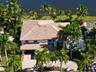 Multi-level residence featuring a tile roof, paved driveway, and mature landscaping on a waterfront lot