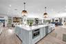 Large kitchen island featuring light blue cabinetry, quartz countertops, farmhouse-style sink, built-in microwave, and wood-finish flooring throughout