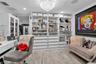 Custom built-in white cabinetry featuring extensive shelving, drawer storage, and glass-front display sections, complemented by wood-finish flooring a