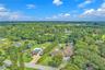 Aerial perspective of extensive acreage featuring a swimming pool, paved driveway, mature trees, and landscaping