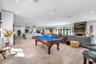 Open-concept interior featuring wood-finish flooring, recessed lighting, a stone-faced fireplace with a timber mantel, and a kitchen island with penda