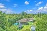 Single-story residence featuring a shingled roof, neutral-toned exterior, integrated covered patio, expansive lawn, and mature perimeter landscaping