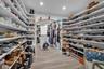 Custom walk-in closet featuring extensive built-in white shelving, recessed lighting, wood-finish flooring, and a central storage island