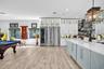 Kitchen featuring custom white cabinetry with glass-front uppers, a stainless steel side-by-side refrigerator, a built-in wine cooler, a stone tile ba