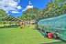 Expansive backyard featuring synthetic turf, a large fabric canopy, a detached storage structure, and a hoop-style greenhouse