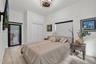 Neutral-toned room featuring wood-finish flooring, a contemporary drum-style ceiling light fixture, built-in double-door closet with overhead cabinet 