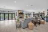 Open-concept living space featuring wood-finish flooring, recessed lighting, floor-to-ceiling multi-panel glass doors, and a floor-to-ceiling stone-su