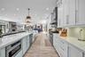 Kitchen featuring floor-to-ceiling white cabinetry, quartz countertops, a professional-grade stainless steel range with a matching hood, a farmhouse-s