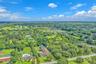Aerial perspective of a sprawling lot featuring mature trees, expansive lawn space, and a multi-section roofline