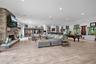 Open-concept living space featuring wood-finish flooring, floor-to-ceiling stone fireplace with a timber mantel, recessed lighting, and a built-in wet