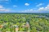 Aerial perspective featuring a multi-pitched shingle roof, expansive manicured grounds, and mature perimeter landscaping