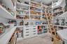 Custom walk-in pantry featuring expansive wall-to-wall shelving, floor-to-ceiling built-in cabinetry with integrated drawers, rolling library-style la