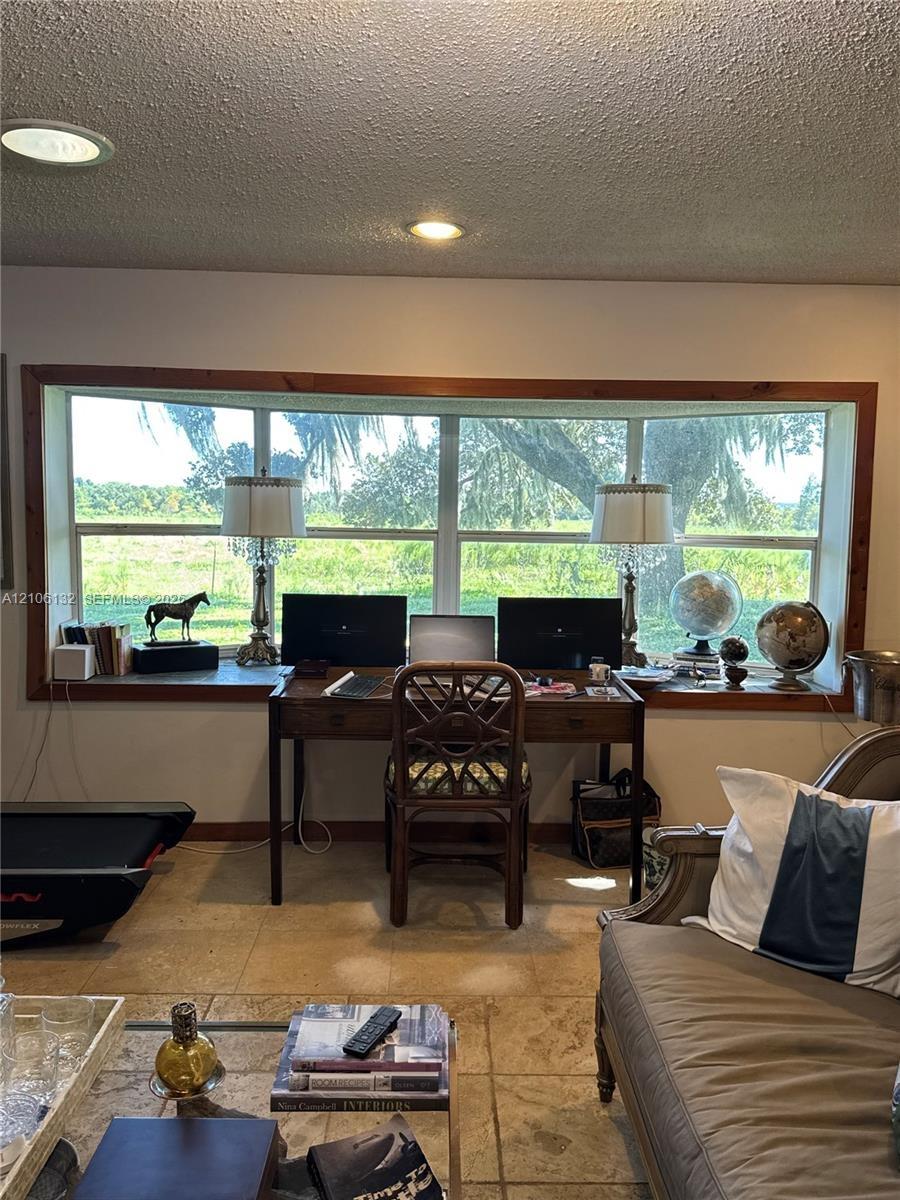 Large picture window featuring wood trim, recessed ceiling lighting, and stone-tile flooring