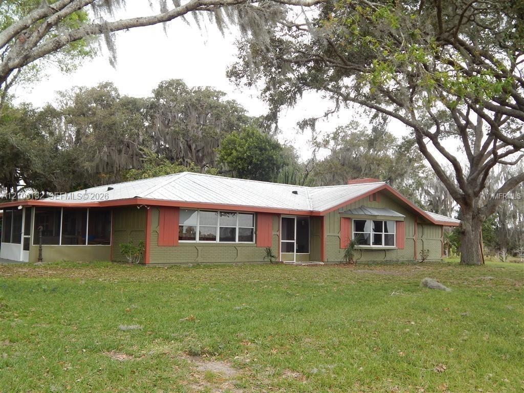 Single-story exterior featuring metal roofing, a screened porch, decorative window shutters, and a bow window
