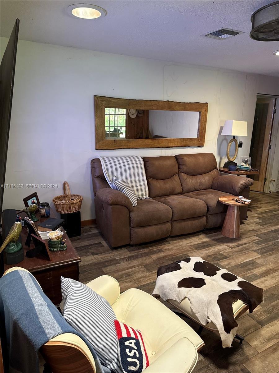 Wood-finish flooring throughout, recessed ceiling lighting, and a custom live-edge wood-framed wall mirror