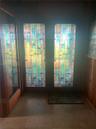 Double entry doors featuring geometric stained-glass inserts, vertical wood paneling, and tile flooring