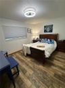 Wood-finish flooring, neutral walls, cellular shade window treatment, and circular LED ceiling fixture