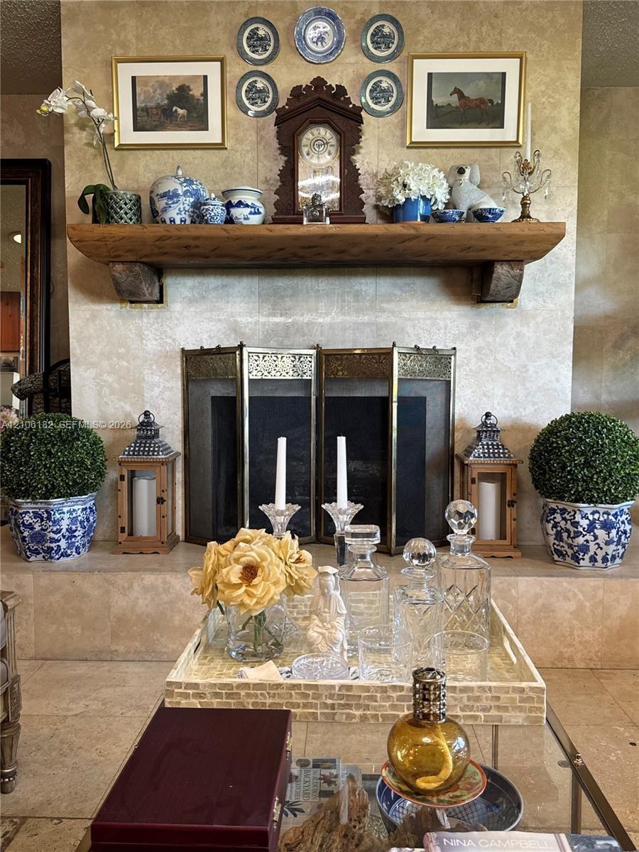 Fireplace featuring floor-to-ceiling natural stone surround, custom wood-beam mantel, and metal folding fire screen