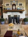 Fireplace featuring floor-to-ceiling natural stone surround, custom wood-beam mantel, and metal folding fire screen