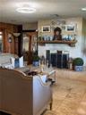 Floor-to-ceiling stone fireplace surround with a natural wood mantel, stone tile flooring, and wood-paneled walls