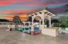 Outdoor oasis featuring a swimming pool, covered pavilion with arched architectural detailing, stone-finish decking, and built-in masonry bar