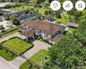 Expansive multi-structure estate featuring a porte-cochere, tile roof, gated entrance, structured landscaping, and a thatched-roof pavilion