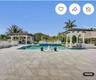Extensive patio area with large-format tile flooring, rectangular pool, dual covered structures with architectural columns, and a tiered fountain feat