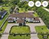 Expansive estate featuring a gated entrance, a paved circular driveway, a porte-cochère, a multi-gabled roofline, and an integrated outdoor pavilion