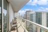 Private covered balcony featuring a glass and metal railing system with panoramic urban skyscraper scenery