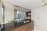 Kitchen featuring dark stone countertops, wood-finish cabinetry with stainless steel pulls, dual-basin undermount sink, porcelain tile flooring, and t