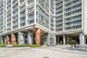 High-rise exterior featuring a multi-story glass facade, private glass-railed balconies, and distinctive sculpted structural columns at the building e