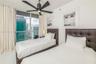 Floor-to-ceiling glass sliding doors with access to a balcony, matte black ceiling fan, and large-format tile flooring