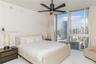 Floor-to-ceiling windows featuring urban skyline scenery, minimalist polished tile flooring, and a contemporary matte black ceiling fan
