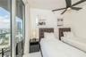 Floor-to-ceiling glass sliding doors, private balcony, matte black ceiling fan, and tile flooring