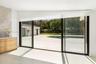 Floor-to-ceiling sliding glass doors, built-in natural wood cabinetry with stone countertop, large format light-toned tile flooring, concrete patio, a
