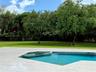 Swimming pool with integrated spa and stone-finish decking, set against a manicured lawn with mature trees