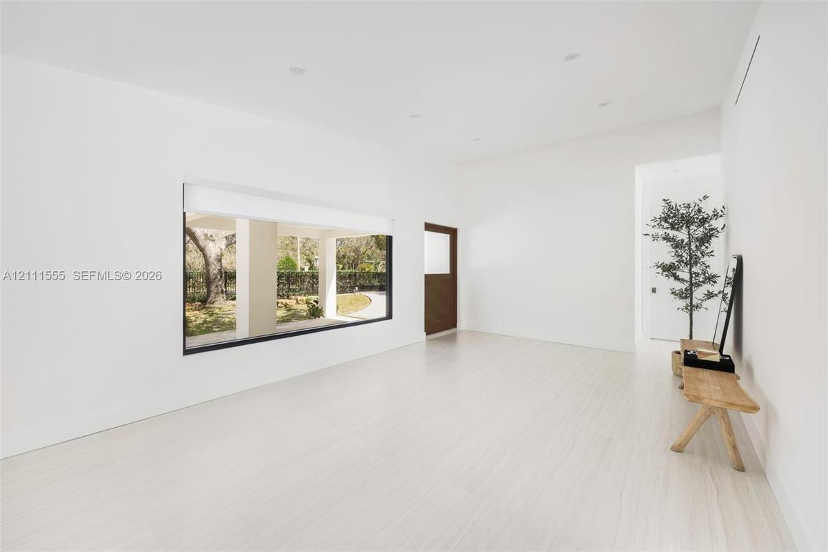 Minimalist interior featuring light-toned flooring, expansive picture window, recessed ceiling lighting, and solid wood door
