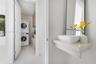 Floating stone vanity with vessel sink and metal faucet, paired with a laundry area featuring a stacked washer and dryer set and custom cabinetry