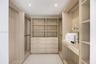 Primary Closet - Hers Custom wood-finish walk-in closet featuring floor-to-ceiling shelving, integrated drawer banks, hanging rods, and recessed light